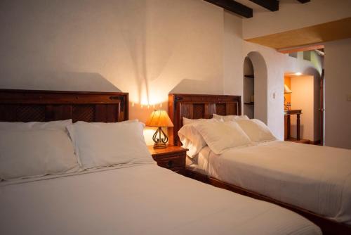 a bedroom with two beds and a lamp on a table at El Alcazar in San Miguel de Allende