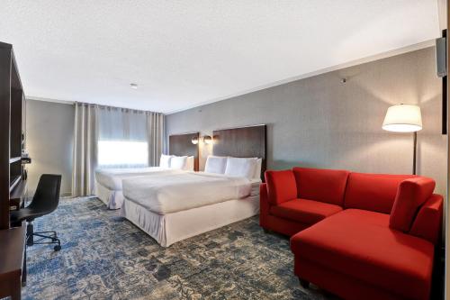 Habitación de hotel con 2 camas y sofá rojo en Four Points by Sheraton Toronto Mississauga, en Mississauga