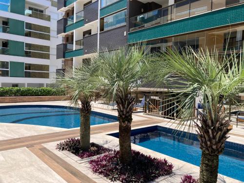 ein Swimmingpool mit zwei Palmen vor einem Gebäude in der Unterkunft Spazio di Patricia in Governador Celso Ramos