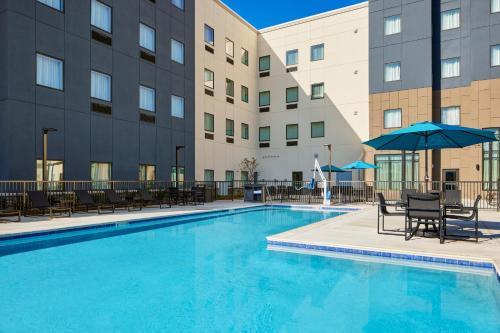 - une piscine avec des chaises et des parasols en face d'un bâtiment dans l'établissement Staybridge Suites - Auburn - University Area, an IHG Hotel, à Auburn