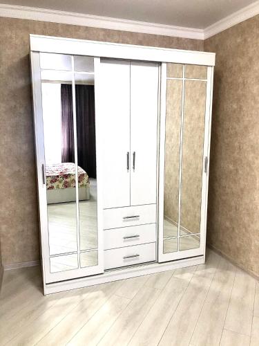 a white cabinet with glass doors in a room at Уютная квартира с новым ремонтом in Leninskoye