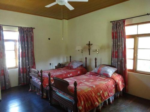 a bedroom with two beds and a ceiling fan at Casa Romero - A cozy tradition in Boquete