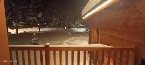 a snow covered yard at night with a fence at Chalet Alpina Hotel & Apartments in La Thuile