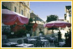 an outdoor patio with tables and umbrellas and chairs at Hotel Krone in Gößweinstein