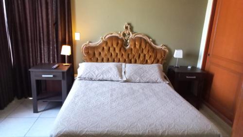 1 dormitorio con 1 cama con cabecero de madera y 2 mesas en Aires del Parque en Salta
