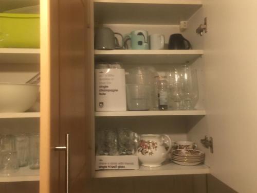 a cupboard filled with dishes and other kitchen items at DACH Apartments - Cozy 3 bed Apartment in Hendon in Colindale