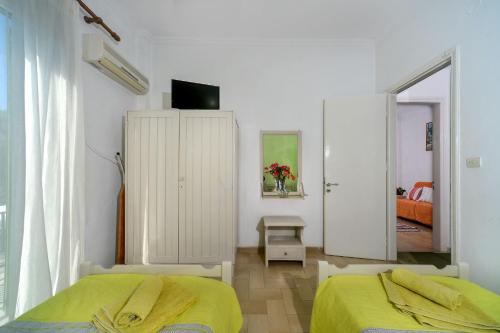 biała sypialnia z 2 łóżkami i lustrem w obiekcie Eirini - LOGGOS APARTMENTS w mieście Longós