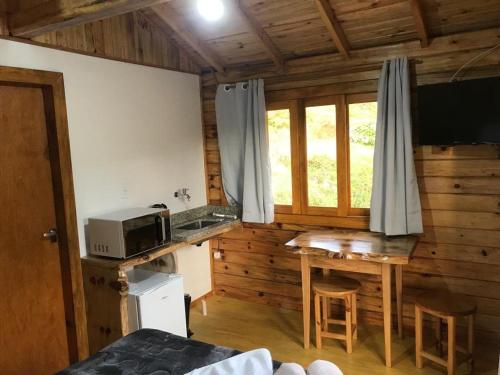 eine Küche mit einer Mikrowelle und einem Tisch im Zimmer in der Unterkunft Cabana da Colina 2 in Bom Jardim da Serra