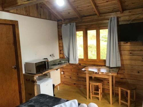 a kitchen with a microwave and a table in a room at Cabana da Colina 2 in Bom Jardim da Serra