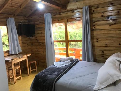 Schlafzimmer mit einem Bett, einem Schreibtisch und einem Fenster in der Unterkunft Cabana da Colina 2 in Bom Jardim da Serra