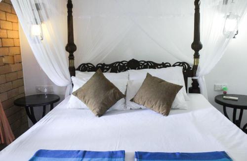 a bedroom with a bed with white sheets and pillows at DANDELION - Unawatuna in Unawatuna