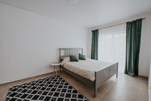 a bedroom with a bed with green curtains and a rug at THE NOOK APARTHOTEL in Timişoara