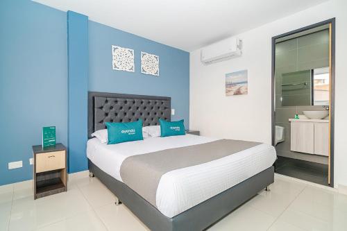 a bedroom with a large bed with blue walls at Ayenda 79 Hotel in Medellín