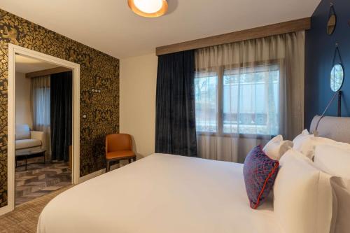a bedroom with a large white bed and a window at Best Western Plus Le Conquerant Rouen Nord in Bois-Guillaume