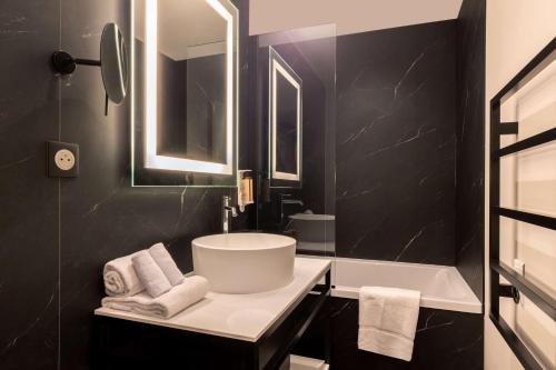La salle de bains noire est pourvue d'un lavabo et d'une baignoire. dans l'établissement Best Western Plus Le Conquerant Rouen Nord, à Bois-Guillaume