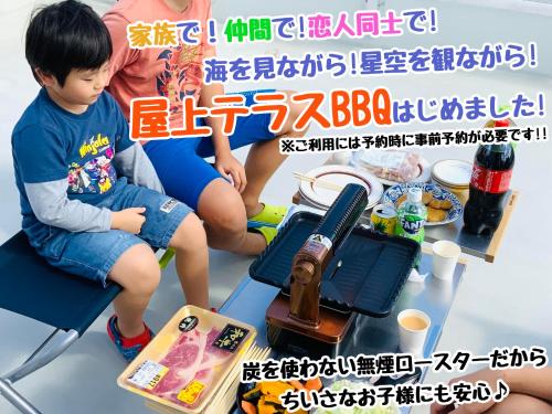 a little boy sitting on a chair next to a table with food at Katsuren Seatopia 勝連シートピア in Uruma