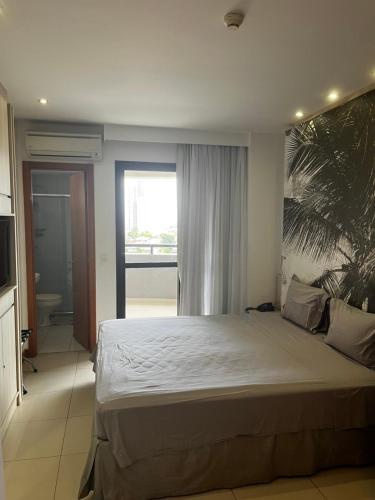 a bedroom with a large bed and a large window at Studio particular em Hotel in Salvador