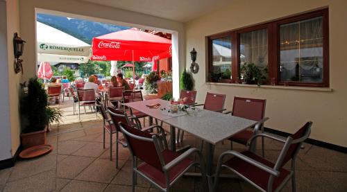 ein Restaurant mit einem Tisch und Stühlen sowie einem Kokosnussschirm in der Unterkunft Dorf Café in Haus im Ennstal