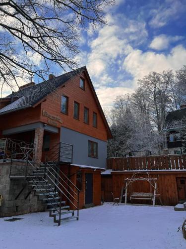 a house with snow on the ground in front of it at Pod Śnieżnymi Kotłami in Piechowice