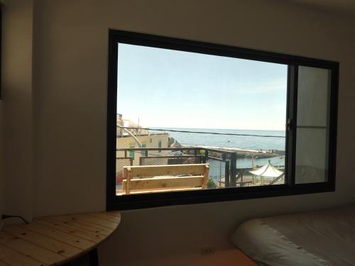 a window in a room with a view of the ocean at Summerflow Hostel in Xiaoliuqiu
