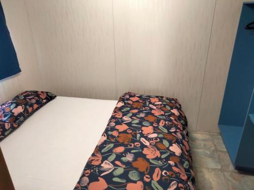 Una cama en una habitación pequeña con una manta de flores. en Beach Haven Caravan Park, en San Remo