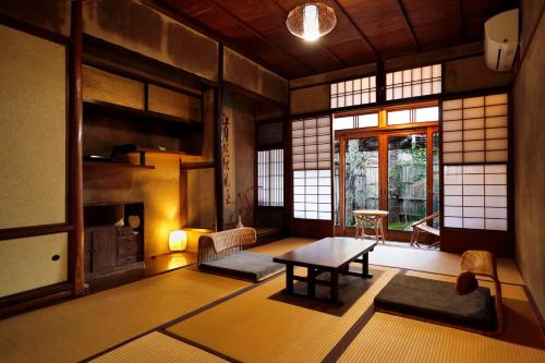 a living room with a table in a room with windows at Azukiya in Kyoto