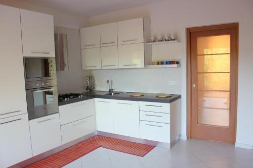 eine weiße Küche mit weißen Schränken und einer Tür in der Unterkunft Appartamento Greta in Porto Azzurro