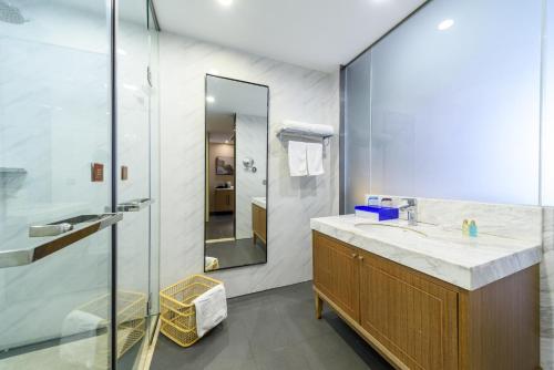 a bathroom with a sink and a glass shower at Qianhai Holiday Hotel in Bao'an