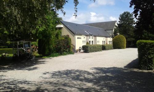 a white building with a black roof and a driveway at Logis Hôtel La Demeure du Perron in Quettehou
