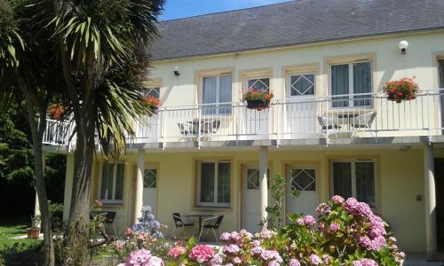a house with chairs and flowers in front of it at Logis Hôtel La Demeure du Perron in Quettehou
