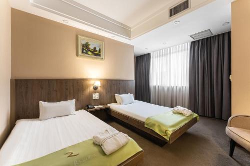 Habitación de hotel con 2 camas y sofá en Renion Residence Hotel, en Almaty