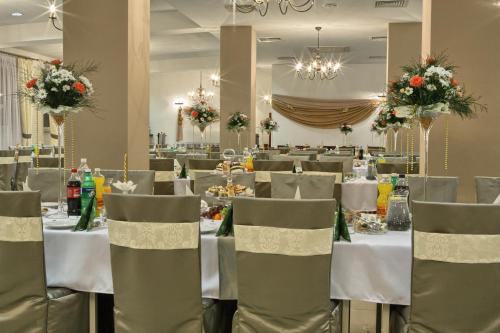 a dining room with white tables and chairs at Hotel Stara Fabryka in Małogoszcz