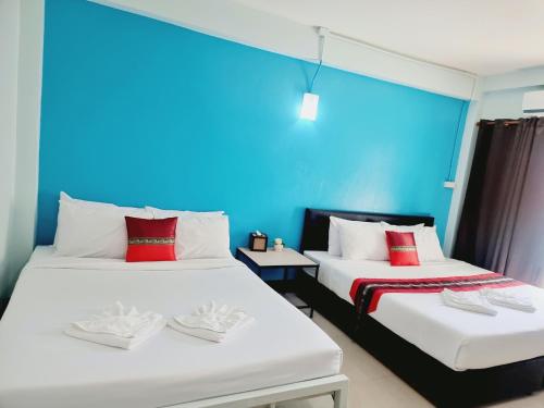 two beds in a room with a blue wall at Chat House Soi 18 Mithuna Chiangrai in Chiang Rai