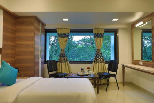 a bedroom with a bed and a table and a window at Imperial Grande Resort in Lonavala