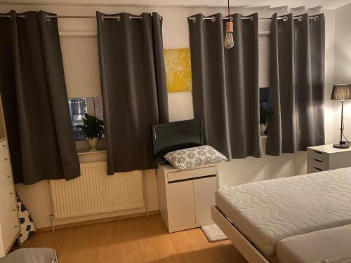 Schlafzimmer mit schwarzen Vorhängen, einem Bett und einem TV in der Unterkunft Privatquartier im Ortskern von Westerstede in Westerstede