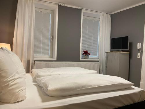 two beds in a bedroom with two windows at Altstadt Fereienwohnung Hameln in Hameln