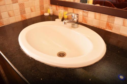 lavabo blanco en el baño con encimera negra en The Siron Place Hotel en Ongata Rongai 