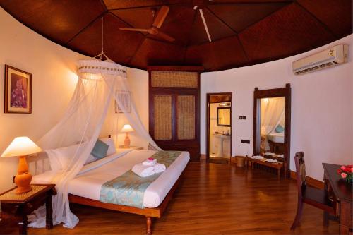 a bedroom with a bed with a mosquito net at Soma Manaltheeram Ayurveda BeachVillage in Kovalam