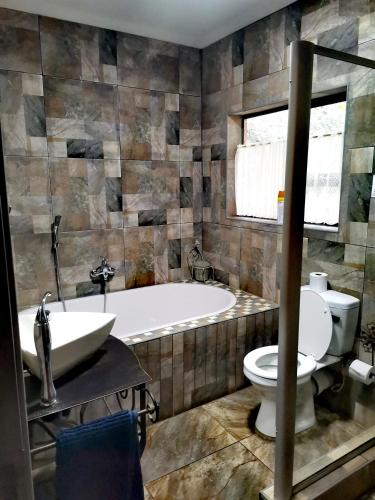 a bathroom with a tub and a toilet and a sink at BUFFALO in Marloth Park