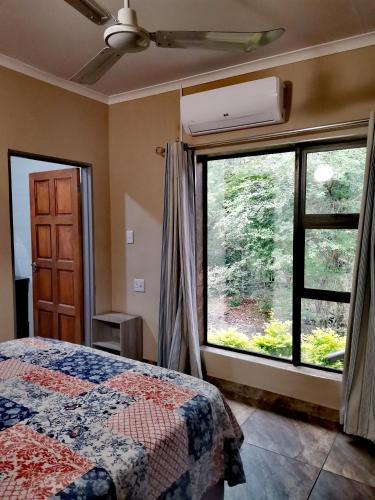 a bedroom with a bed and a large window at BUFFALO in Marloth Park