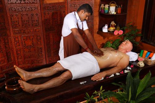 a man giving a man a bath in a bath tub at Soma Manaltheeram Ayurveda BeachVillage in Kovalam