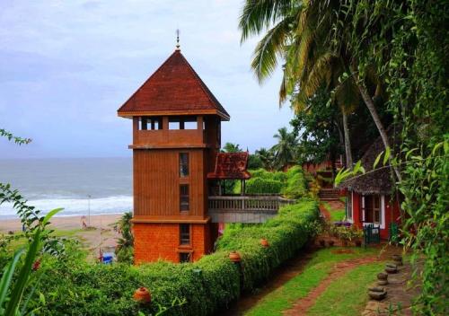 a building with a tower next to the beach at AyurSoma Ayurveda Royal Retreat in Kovalam
