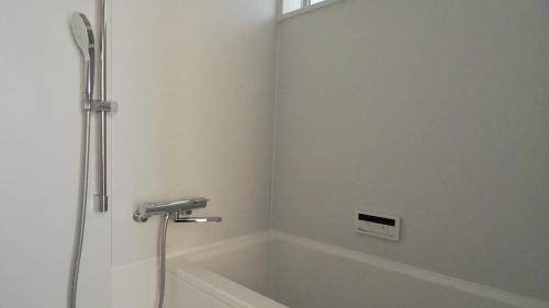 La salle de bains est pourvue d'une baignoire et d'une douche. dans l'établissement HUB INN, à Onomichi