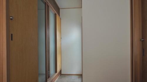 einen Flur mit Glastür und Spiegel in der Unterkunft HUB INN in Onomichi