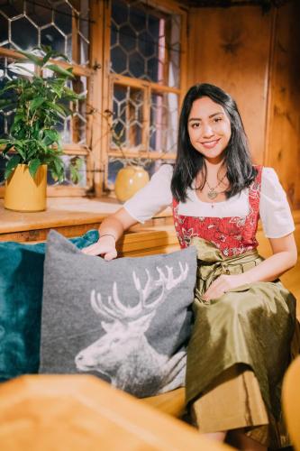 a woman sitting on a couch with a picture of a deer at Gasthaus Rössle in Nenzing