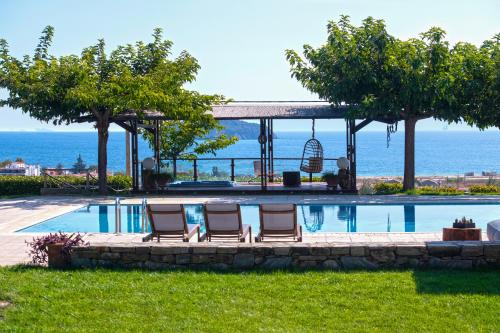 a swimming pool with two chairs and a swing at Ferenity in Iraklitsa