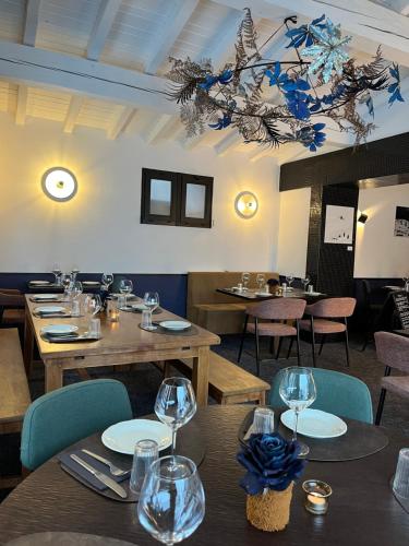 un restaurante con mesas y sillas de madera y una lámpara de araña en Relais Des Villards, en Séez