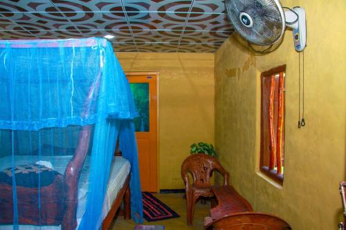 a room with a bed and a fan and chairs at Relax Nature Villa in Sigiriya
