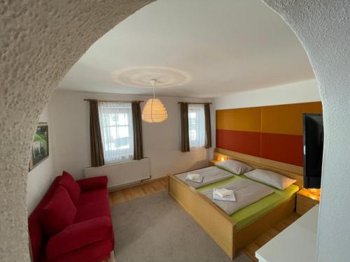 ein Wohnzimmer mit einem Bett und einem roten Sofa in der Unterkunft Naturgut Gailtal in Sankt Stefan an der Gail