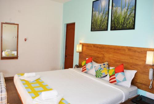 a bedroom with a large white bed with colorful pillows at EDEN Paradisee in Ooty
